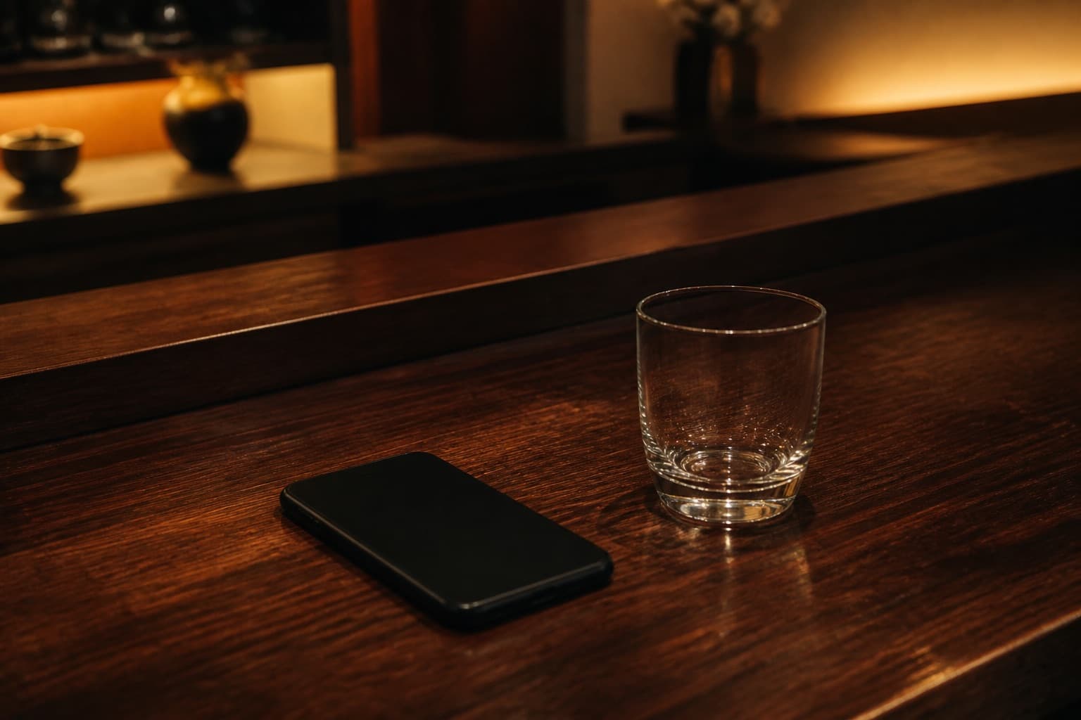 バーカウンターに伏せて置かれたスマートフォンとグラス
